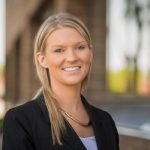 Amanda Hanson smiles for a head shot photo in front of a blurred background